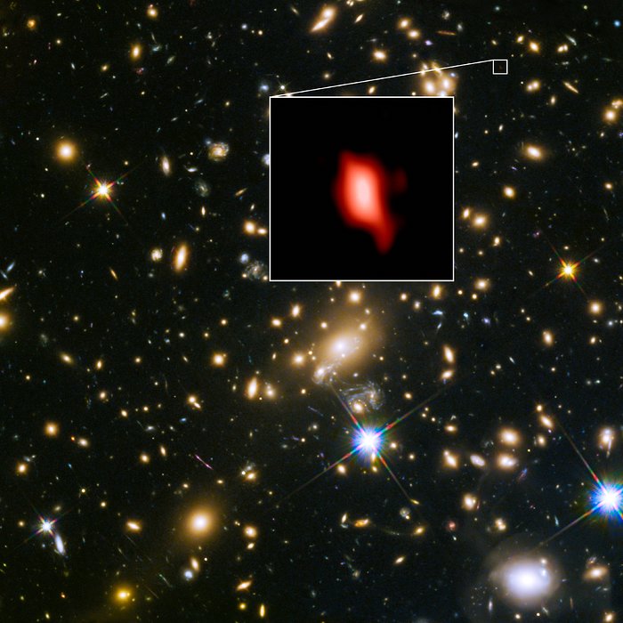 This image shows the galaxy cluster MACS J1149.5+2223 taken with the NASA/ESA Hubble Space Telescope; the inset image is the very distant galaxy MACS1149-JD1, seen as it was 13.3 billion years ago and observed with ALMA. Here, the oxygen distribution detected with ALMA is depicted in red.